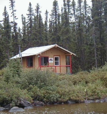 a cabin on a lake with a boat in the water