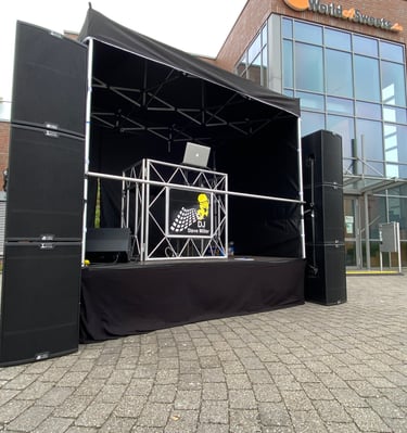 Professionelles Outdoor-DJ-Bühnen-Setup mit großen schwarzen Lautsprechern und Equipment für Events