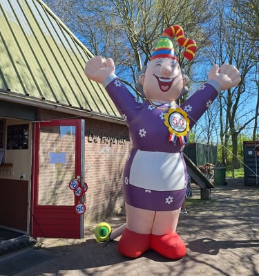 Opblaaspop Sarah, Feestelijke muts op aan de voorkant van een restaurant. Gekleed in Paarse jurk
