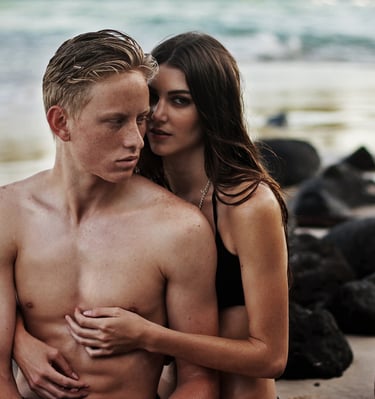 a young male female couple in a romantic moment at a beach with volcanic rock at one of the beach