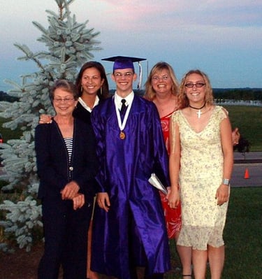 A high school graduate in a purple cap and gown poses with family outdoors at sunset. Athens, Oh
