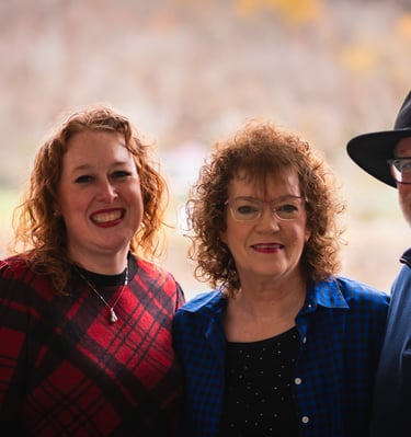 A happy group of four smiling adults posing for a family portrait outdoors during autumn.
