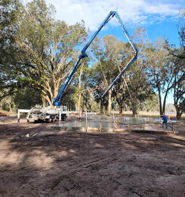 Boom pump pumping comcrete in rural area with trees in background.
