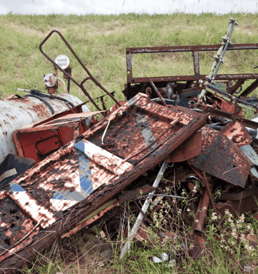 A large pile of junk including old metal doors, tanks, old fencing, old broken lawnmowers, and more.