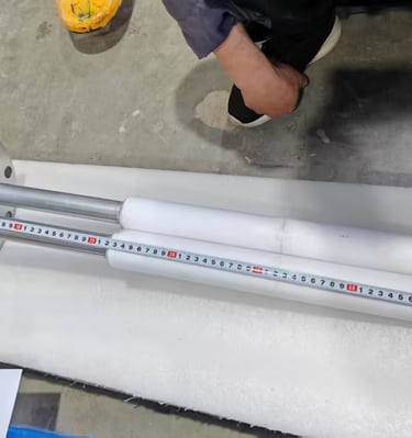 Industrial immersion heater with protective ceramic sleeves being measured with a tape rule.