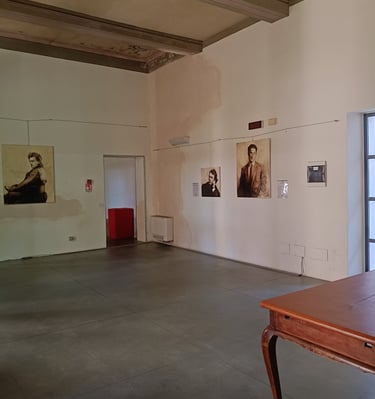 Cesare Pavese portrait paintings hanging on white walls and a vintage wooden desk.