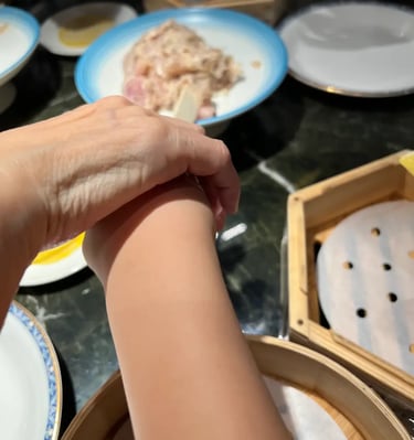 製作燒賣 「 親子燒賣課程一雙手正在製作燒賣，旁邊放有蒸籠與食材盤，呈現中式點心課堂的動手實踐與細膩操作。