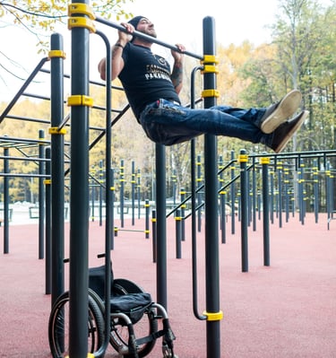 Homme en fauteuil roulant faisant des tractions sur une barre de traction  Kenguru Pro