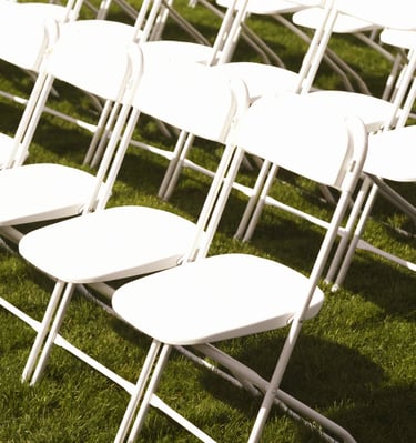 Sillas blancas plegables para eventos al aire libre en el paso