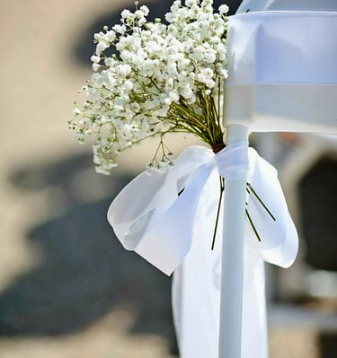 Silla para boda decorada con un liston blanco y flores