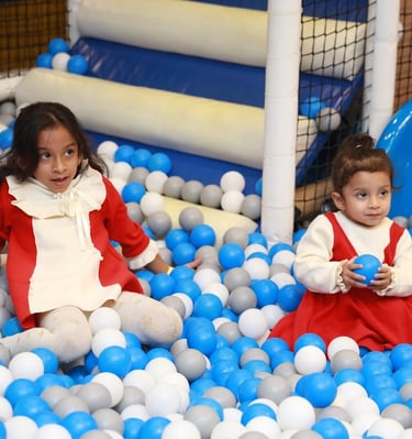 two young girls in red and white dresses playing in a ball pit