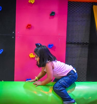a young girl is playing on a slider in a play area