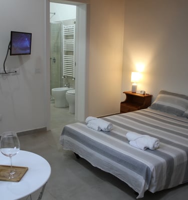 Lodgings in Sardinia a bedroom with a bed and a table with wine glasses