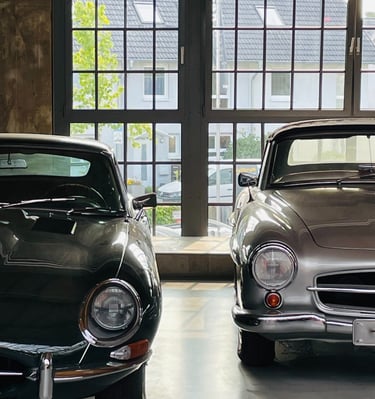 Jaguar & Mercedes Benz sharing stories while parked in a garage