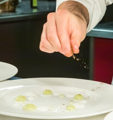 uno chef che condisce il suo piatto