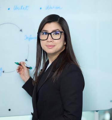 a woman in a suit and glasses is standing in front of a white board