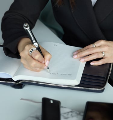 a woman in a suit writing on a notebook