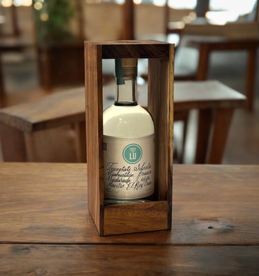 Botella de Lu Mezcal Tepextate Silvestre en una mesa de madera