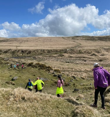 Runners heading down a slope across Dartmoor