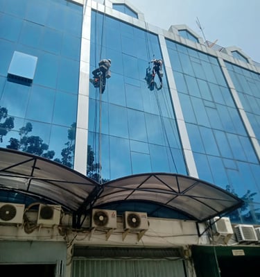 a man is cleaning a building with a window cleaner