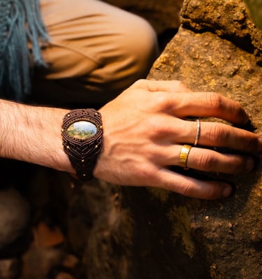 a man's hand wearing woven cuff with semi precious stone and wearing 2 rings