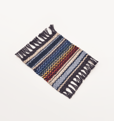 a hand-woven mug rug coaster with rainbow pride flag colours