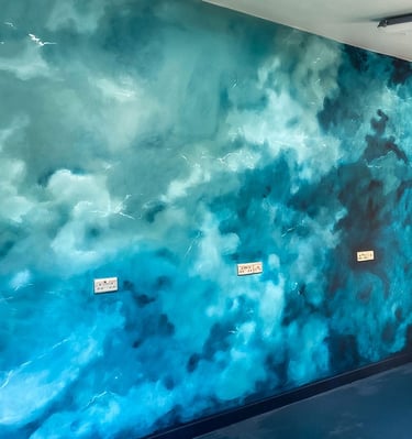 Angled view on mural with teal stormy clouds and a bit of stylised brain in pink and teal colours. 