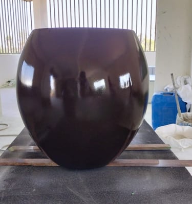 a large brown vase with a large black object in the background
