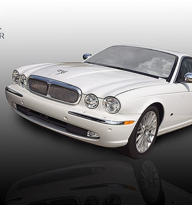 A white Jaguar XJ luxury sedan with chrome trim and signature hood ornament on a gradient background.