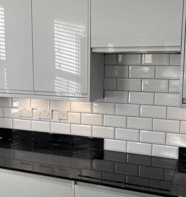 Modern kitchen featuring white gloss cabinets, black quartz countertops, and a white subway tile backsplash.