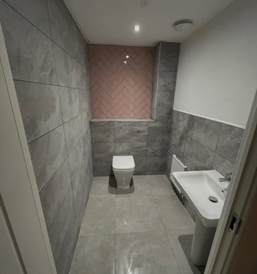Modern bathroom featuring grey stone tiles and a pink herringbone accent wall.