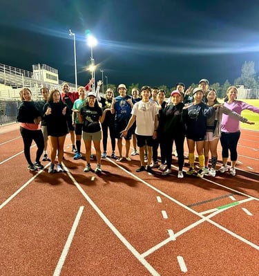 a group of people standing on a track with Coach Ray Z after barefoot training class