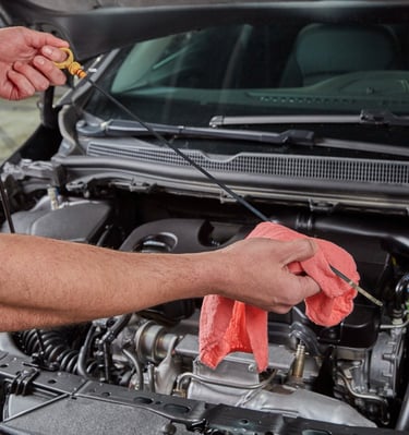 Big O Tires employee checking engine oil