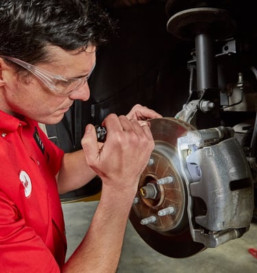 A Big O Tires employee inspecting a brake