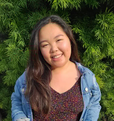 Elizabeth Nguyen, LMFT smiling with a green, luscious bush behind her