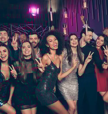 Large group of friends enjoying a night out at a Las Vegas club crawl, smiling and making peace signs during the lively party