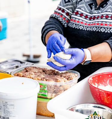 A food vendor wearing blue gloves prepares traditional dough at the Afro Fiesta Festival.