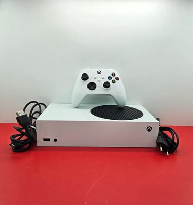 White Xbox Series S gaming console with wireless controller and power cables on a red surface.