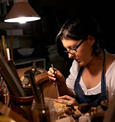 ARTESANA JOYERA TRABAJANDO CON CINCEL PARA MOLDEAR UN ANILLO DE CUARZO AMATISTA