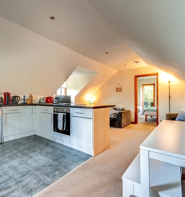 Modern studio apartment kitchen with white cabinets, breakfast bar, and sloped ceilings.