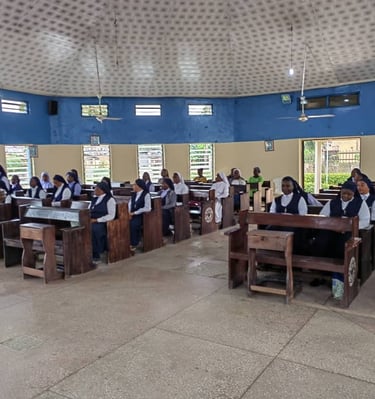Catholic nuns wearing habits sitting in wooden pews during a church service in a circular chapel.