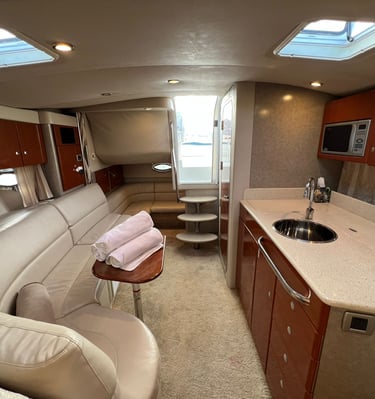 Luxury motor yacht interior featuring a leather sofa, galley kitchen, and wooden cabinetry.