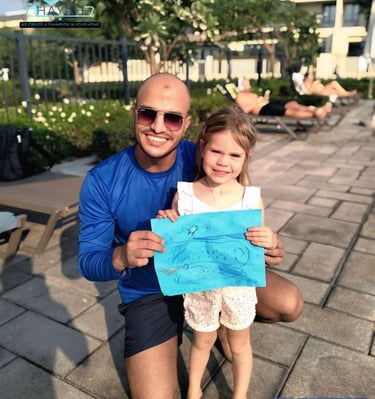 Smiling private swim coach and young student holding a drawing by a swimming pool.