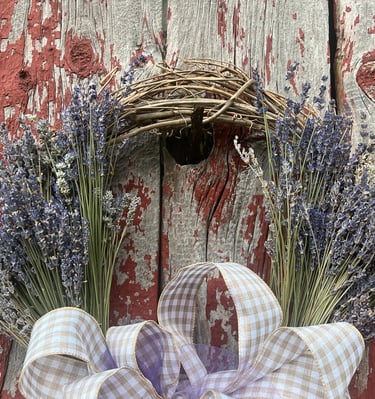 a wreath made of dried lavender flowers on a red barn door