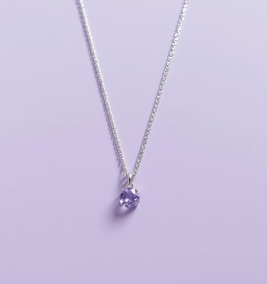 Elegant sterling silver necklace featuring a round purple amethyst pendant on a light purple background.