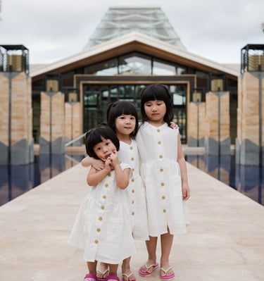 Two sisters standing together at the iconic entrance walkway of The Mulia Nusa Dua Bali during a family photo session