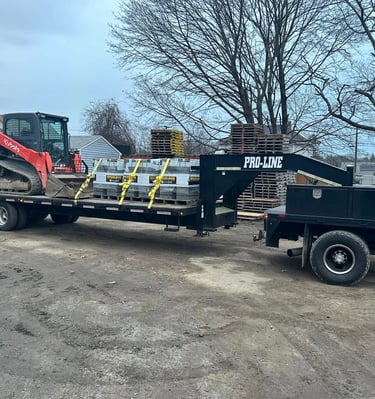 A red Kubota compact track loader and construction supplies on a black Pro-Line gooseneck trailer.