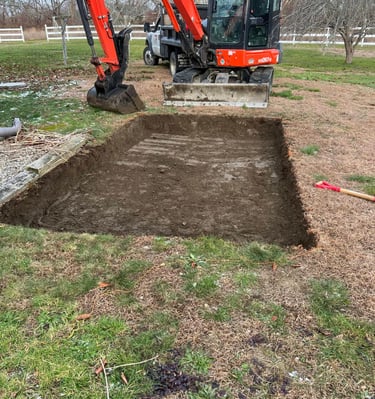 Orange Kubota mini excavator completing a precise rectangular ground excavation for a backyard project.