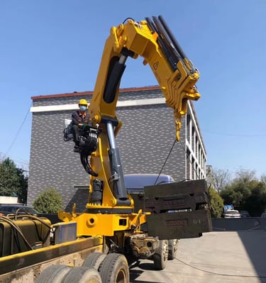A large object being raised by a crane, specifically a 25 Ton Knuckle Loader Crane.