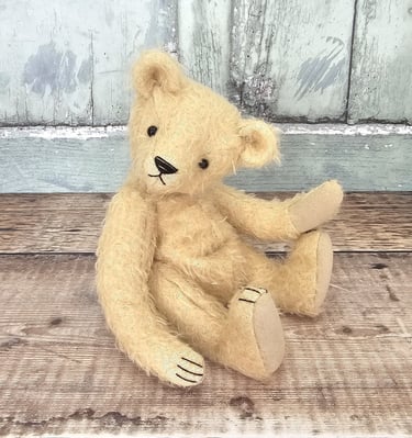 a little hand made teddy bear sitting on a table